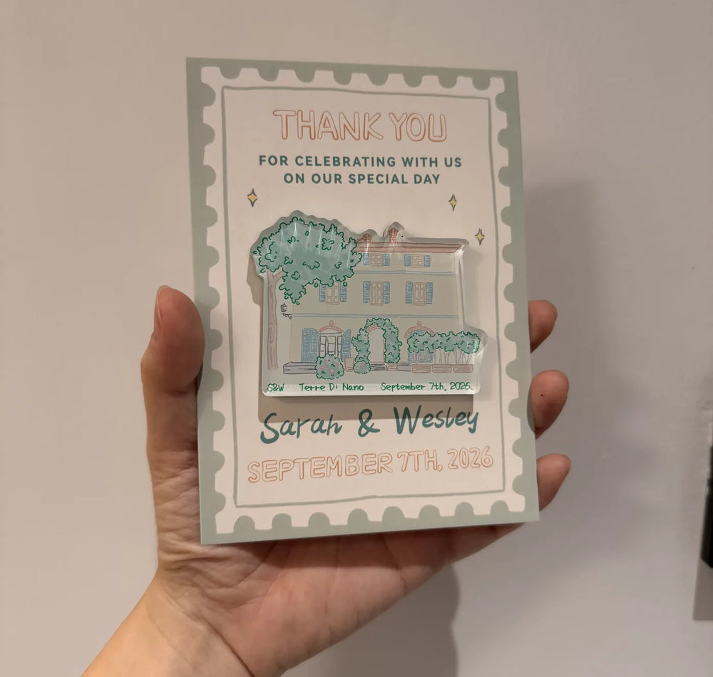 Hand holding a Terre di Nano venue illustration magnet on a decorative pink backing card.