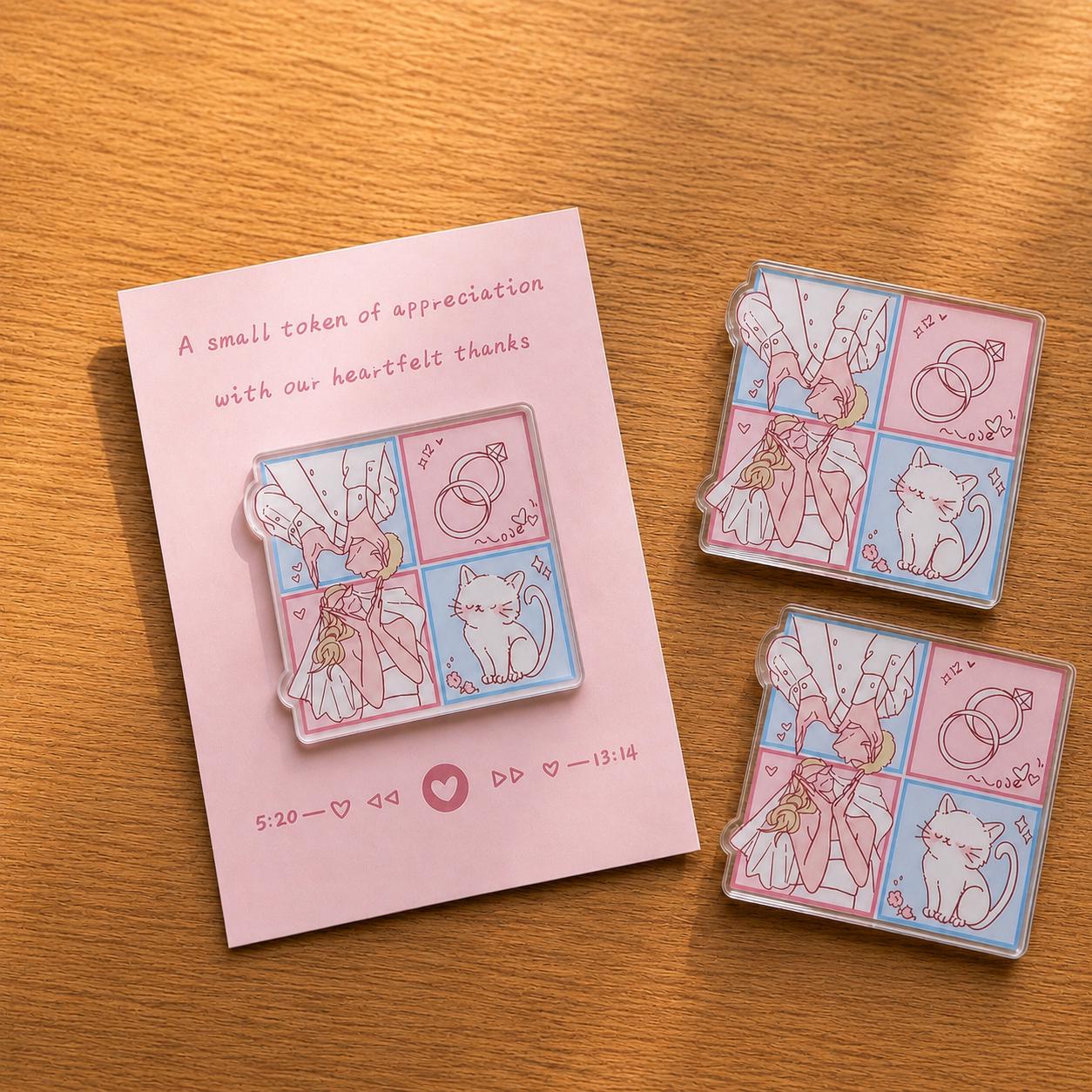 Three acrylic magnets with a pink and blue wedding comic of a couple, rings, and a cat