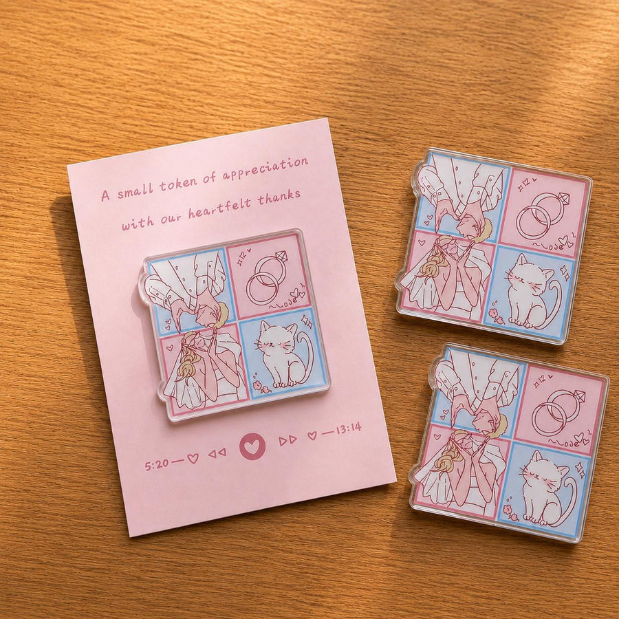 Three acrylic magnets with a pink and blue wedding comic of a couple, rings, and a cat